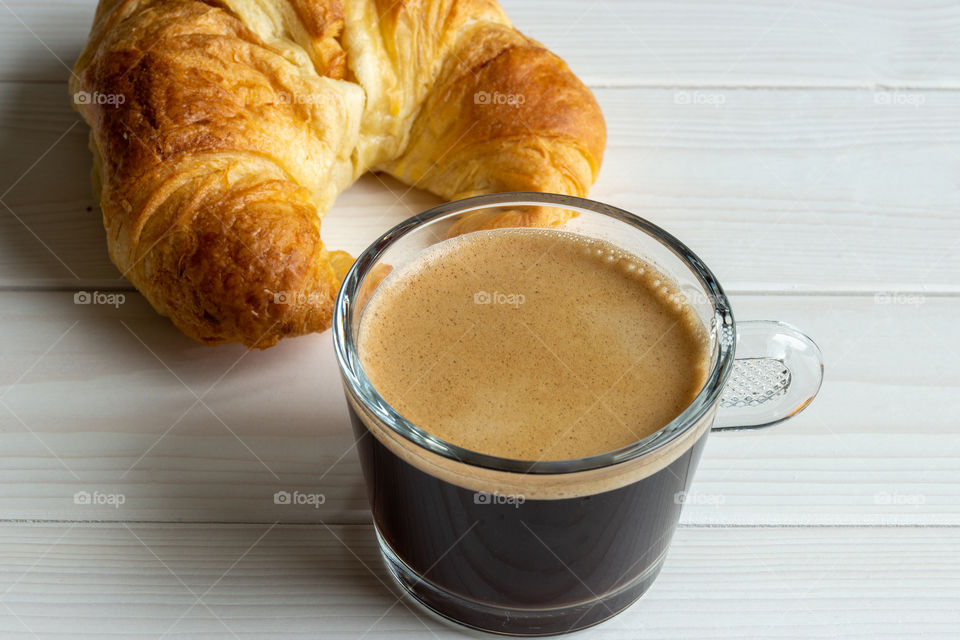 glass of black coffee and croissant