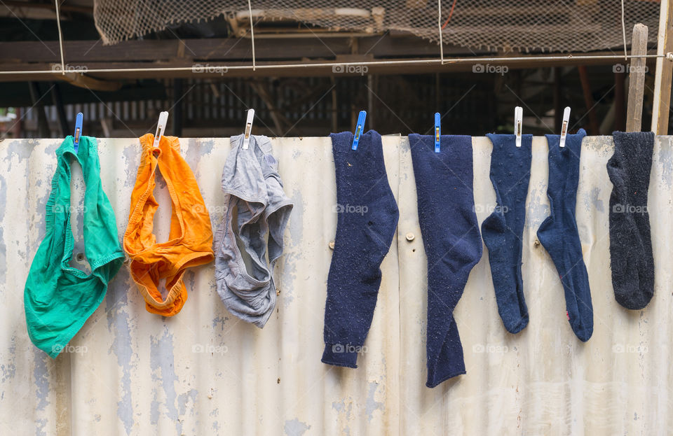 Men's socks and underpants drying on an old tin fence at the side of a work shed.