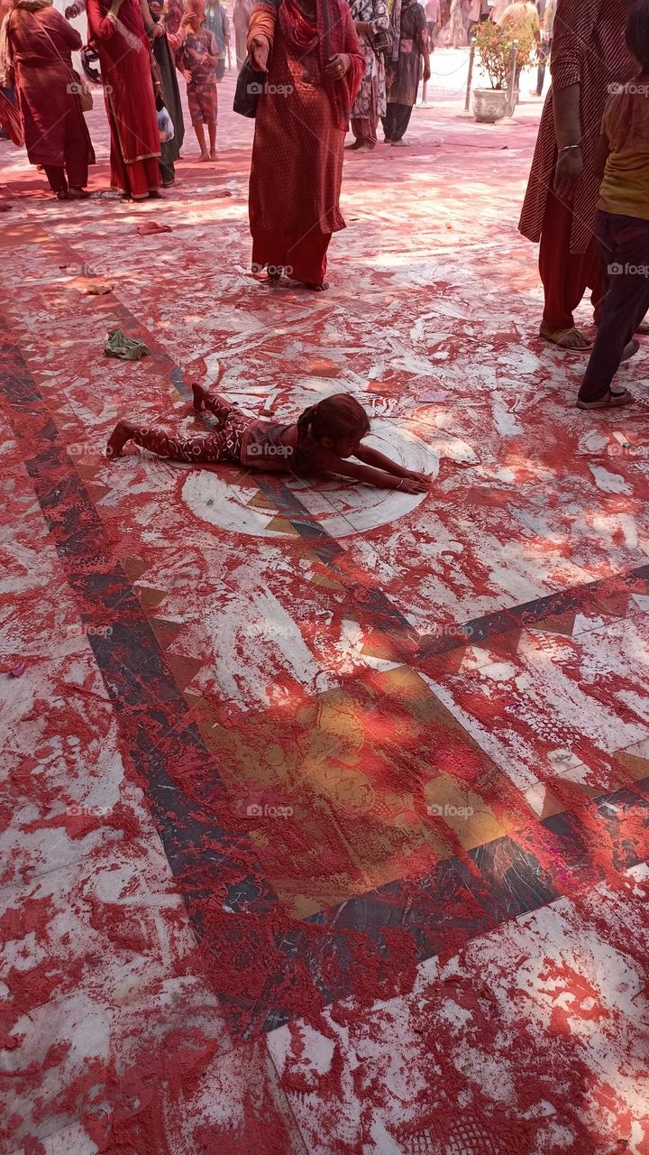 holi festival is celebrated in India. in the month of March . kids enjoy it a lot. so much colour  is on the floor with which the child is playing.