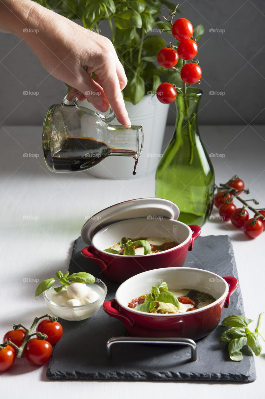 hot Italian caprese salad with baked tomatoes, mozzarella cheese, pesto in portioned casseroles