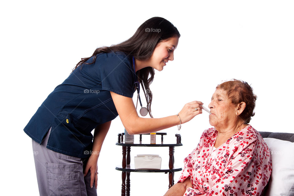 Nurse doctor measuring fever temperature on senior woman
