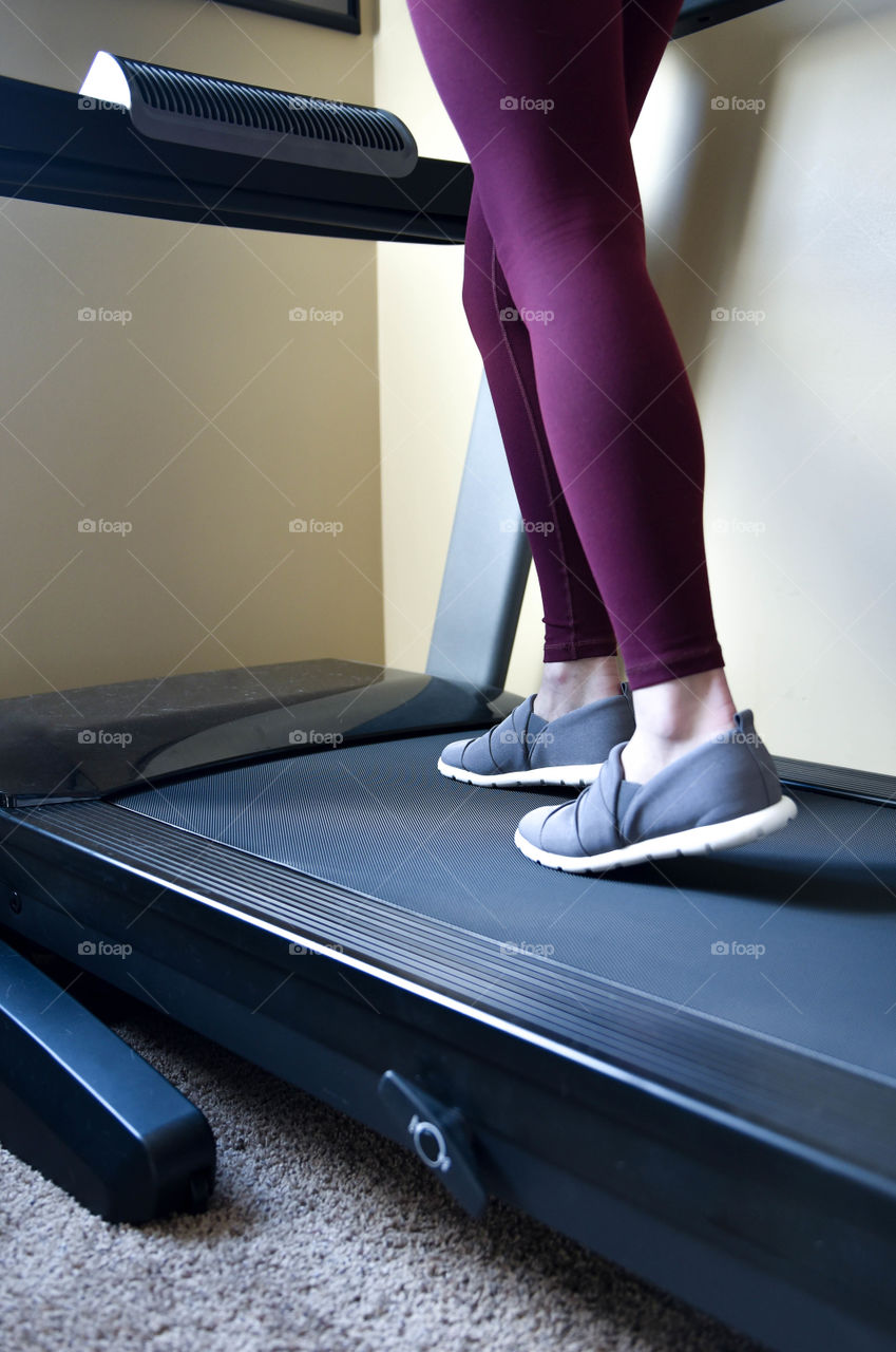 Close-up of a woman's legs on a treadmill in a home gym