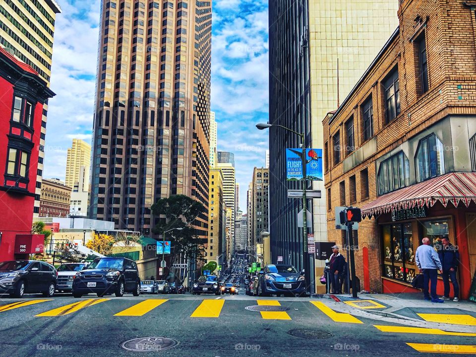 Down town San Francisco. Building with a blue sky with clouds. Traffic heading toward camera.