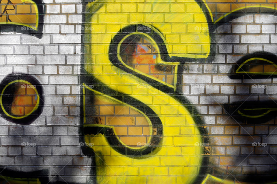 Yellow graffiti on brick wall in Berlin, Germany.