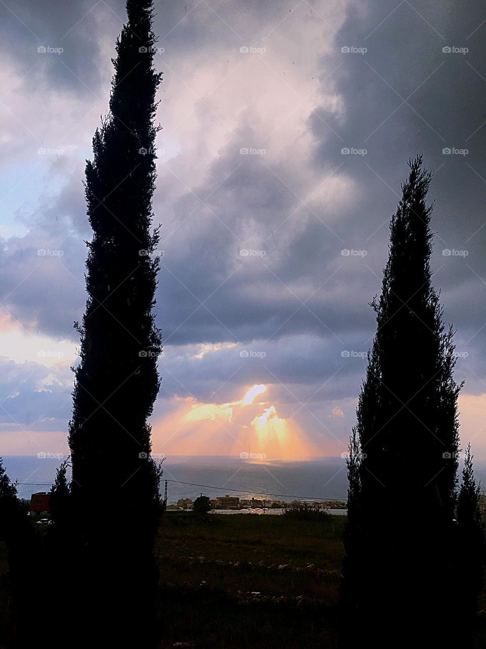 The sun disappears behind the clouds, but its rays shine with light on the sea.