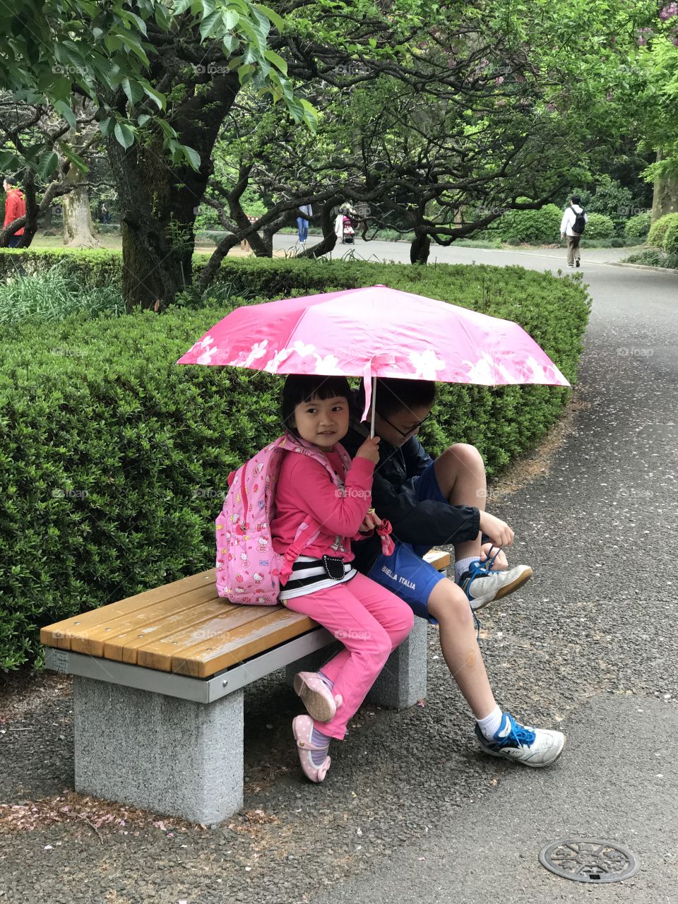 Shinjuku-Gyoen Park on a rainy day portrayed by kids sharing umbrellas