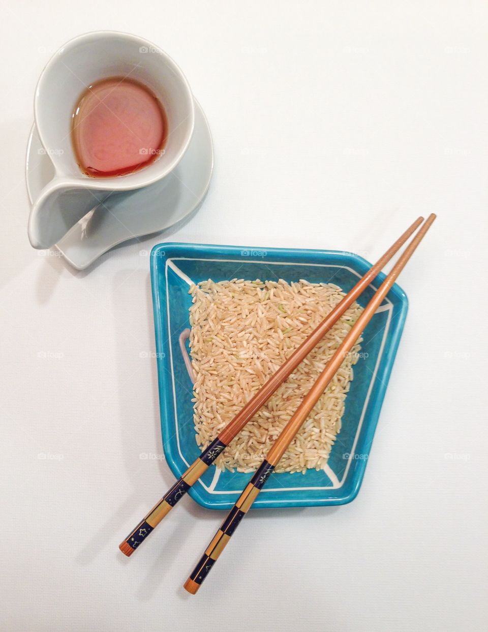 Empty tea cup and rice with chopsticks