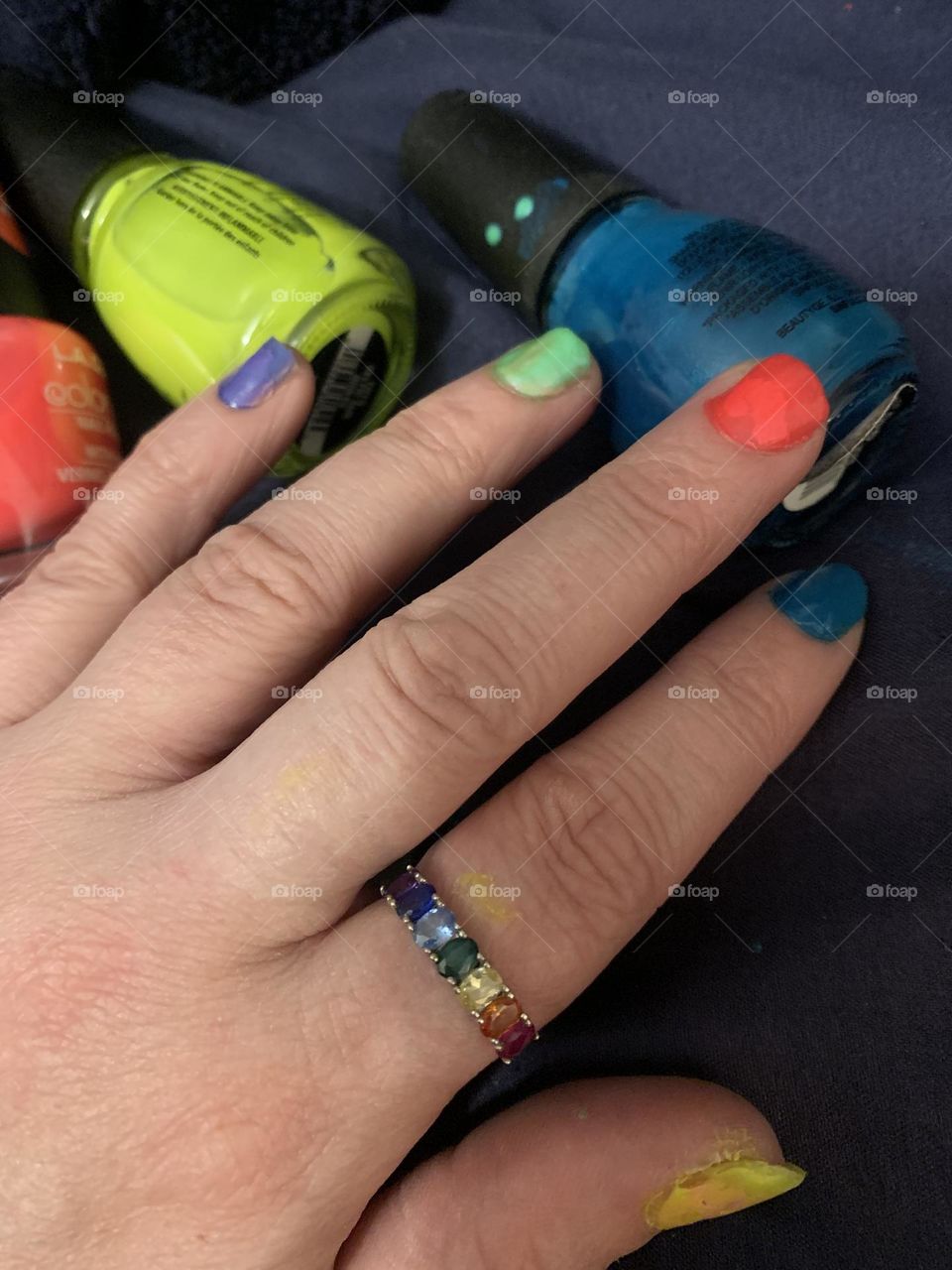 Hand wearing pride colour rainbow nail polish and ring