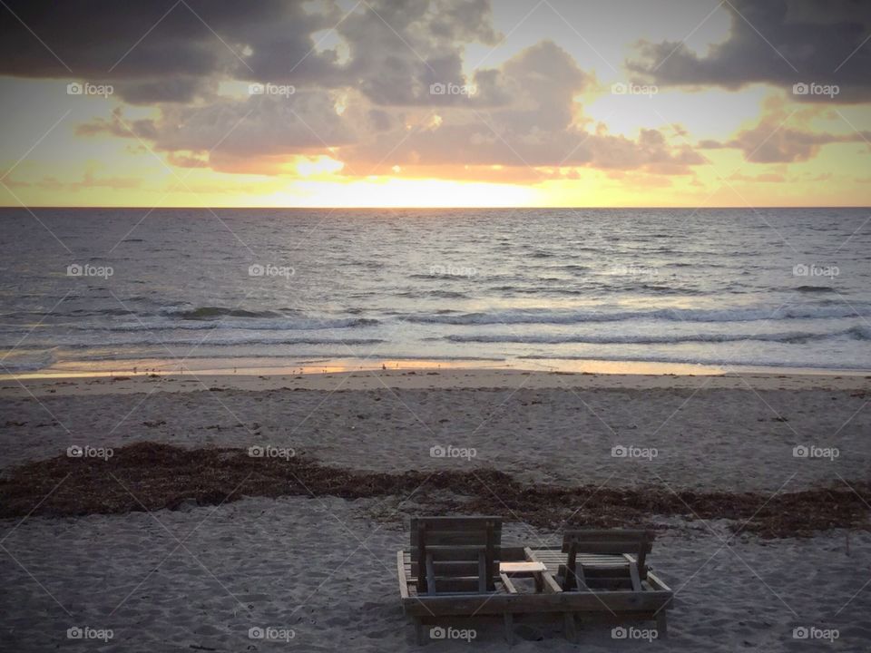 Two wood chairs on the beach unoccupied 