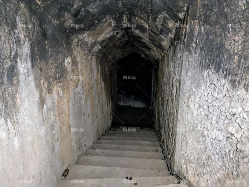 Old stone staircase that gets darker as you move down into the tunnel. The walls are blackened toward the top.