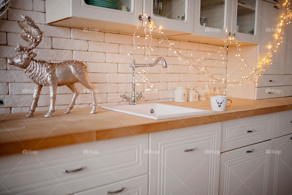 Festive winter cozy kitchen interior with garlands, decorations and gifts.  Christmas dinner at the decorated table.