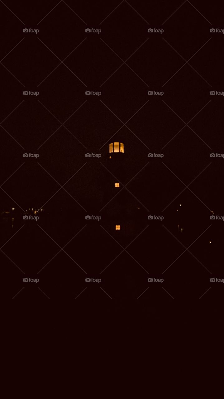 Night is Now coveting lake shore Distant Shore Lighting Show Reflections over Lake Waters. Lighthouse Lighting is now Providing passage.