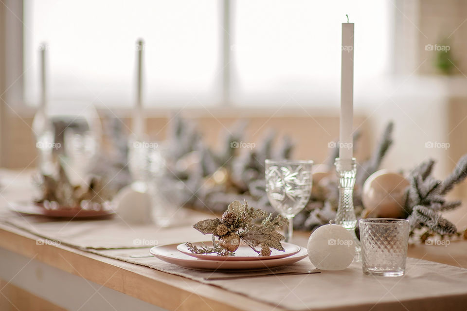 Festive winter cozy kitchen interior with garlands, decorations and gifts.  Christmas dinner at the decorated table.