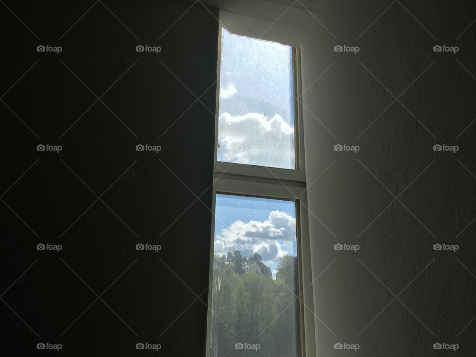 Tall window with trees and clouds and blue sky