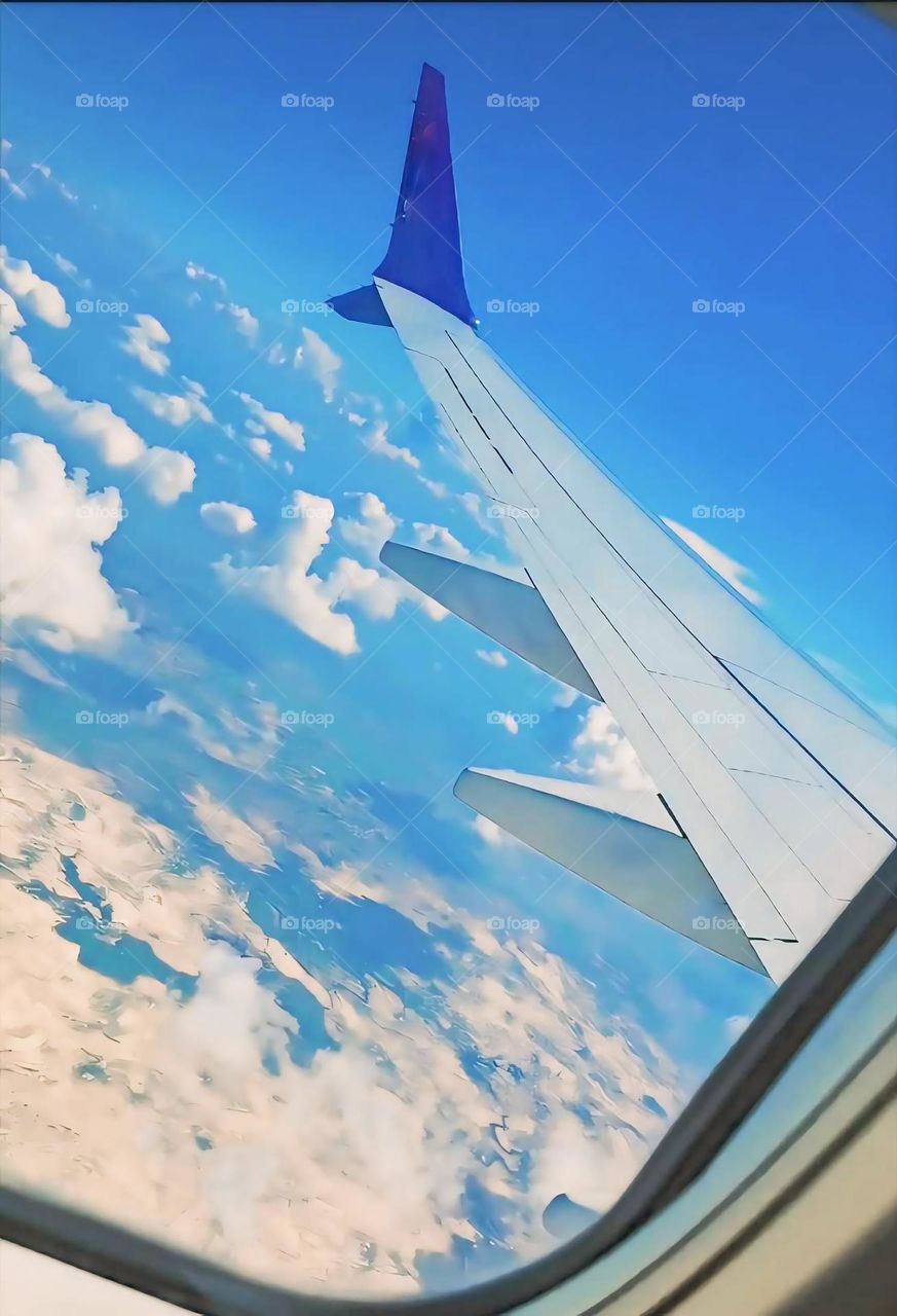 A view from an airplane window showcasing the aircraft's wing against a clear blue sky