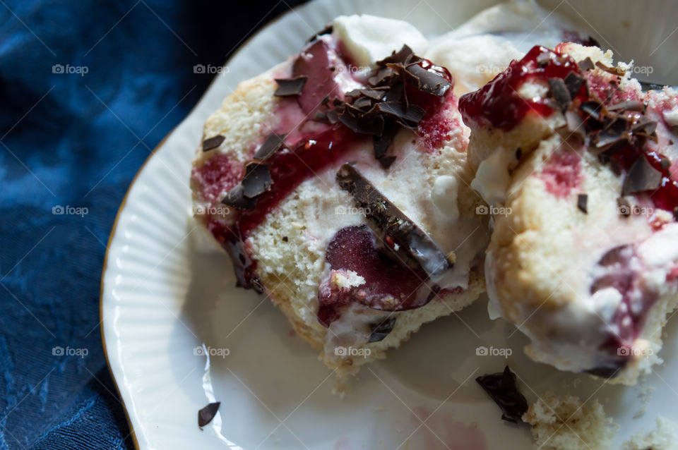 Elegant home made ice cream sandwich dessert on plate for summer entertaining or dinner party made with fresh homemade lady fingers, vanilla ice cream, layered with dark chocolate and cherries topped with cherry coulis sauce