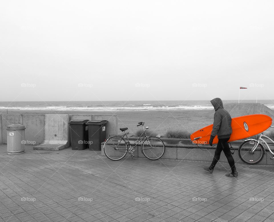 Person walking with red surfboard at seaside