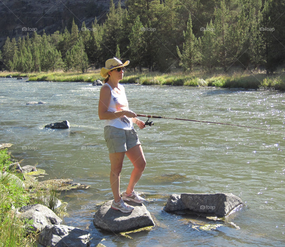 Young woman holding fishing rod in river