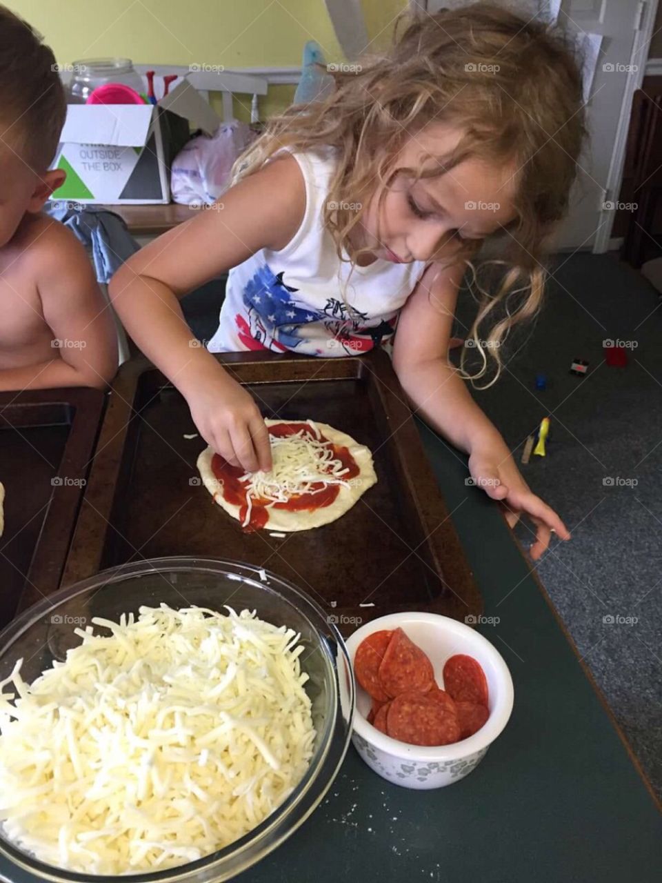 A little girl concentrating on making the perfect pizza. 