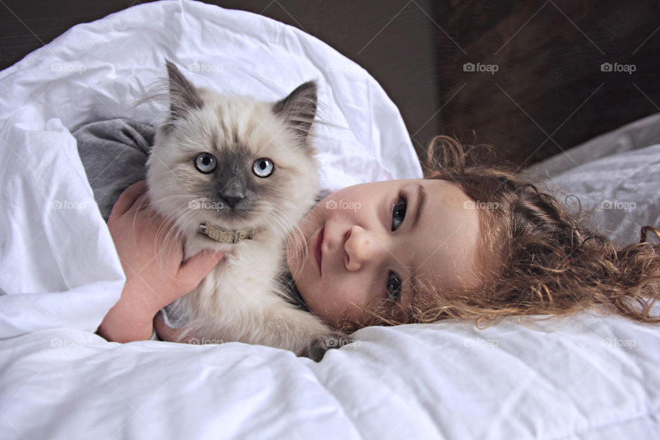 Girl and cat lying on bed