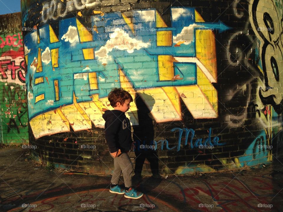 A boy walking in front of street art