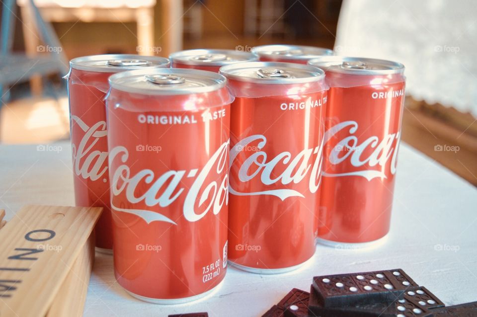 A six pack of Coca-Cola cans with dominos 