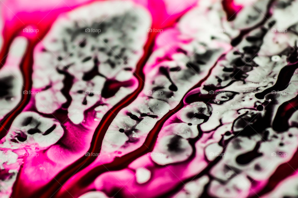 Black and pink refill ink spilled onto the white sink and the ink mixed into abstract blobs and patterns.
