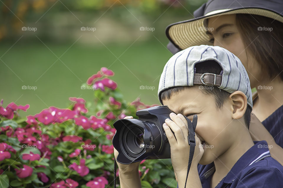 Hand boy holding the camera Taking pictures in park.