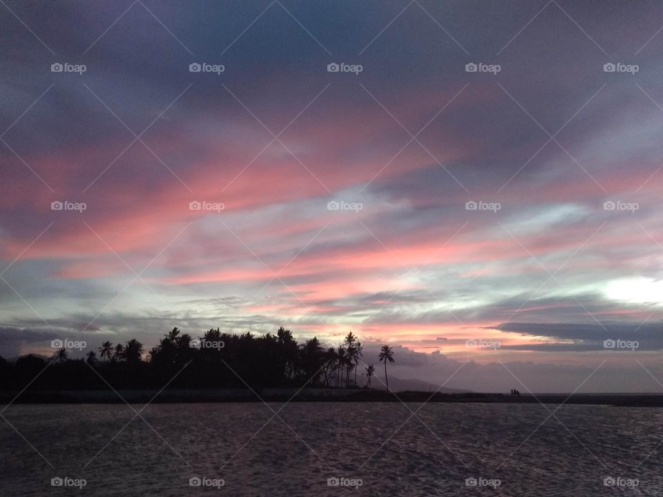 Beautiful pink sunset by the river and sea,  coconut trees outlines