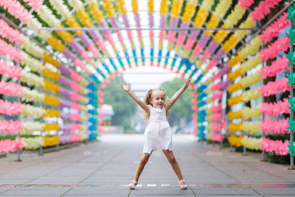 Little girl with blonde jumping in colorful tunnel 
