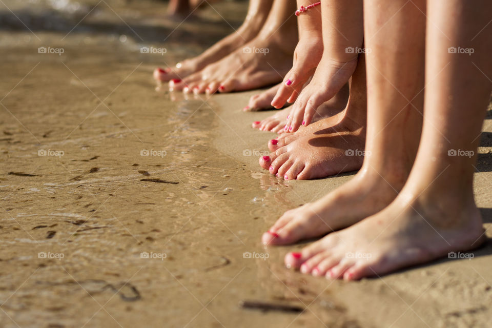 women's feet on the beach. mother and daughters on the beach barefoot