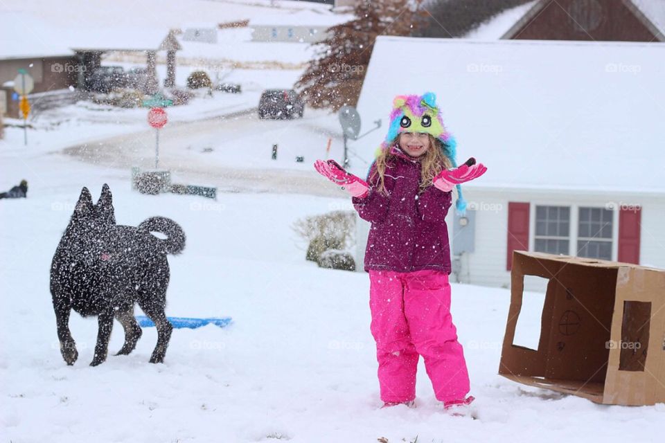 Portrait of happy girl with dog enjoying in the snow