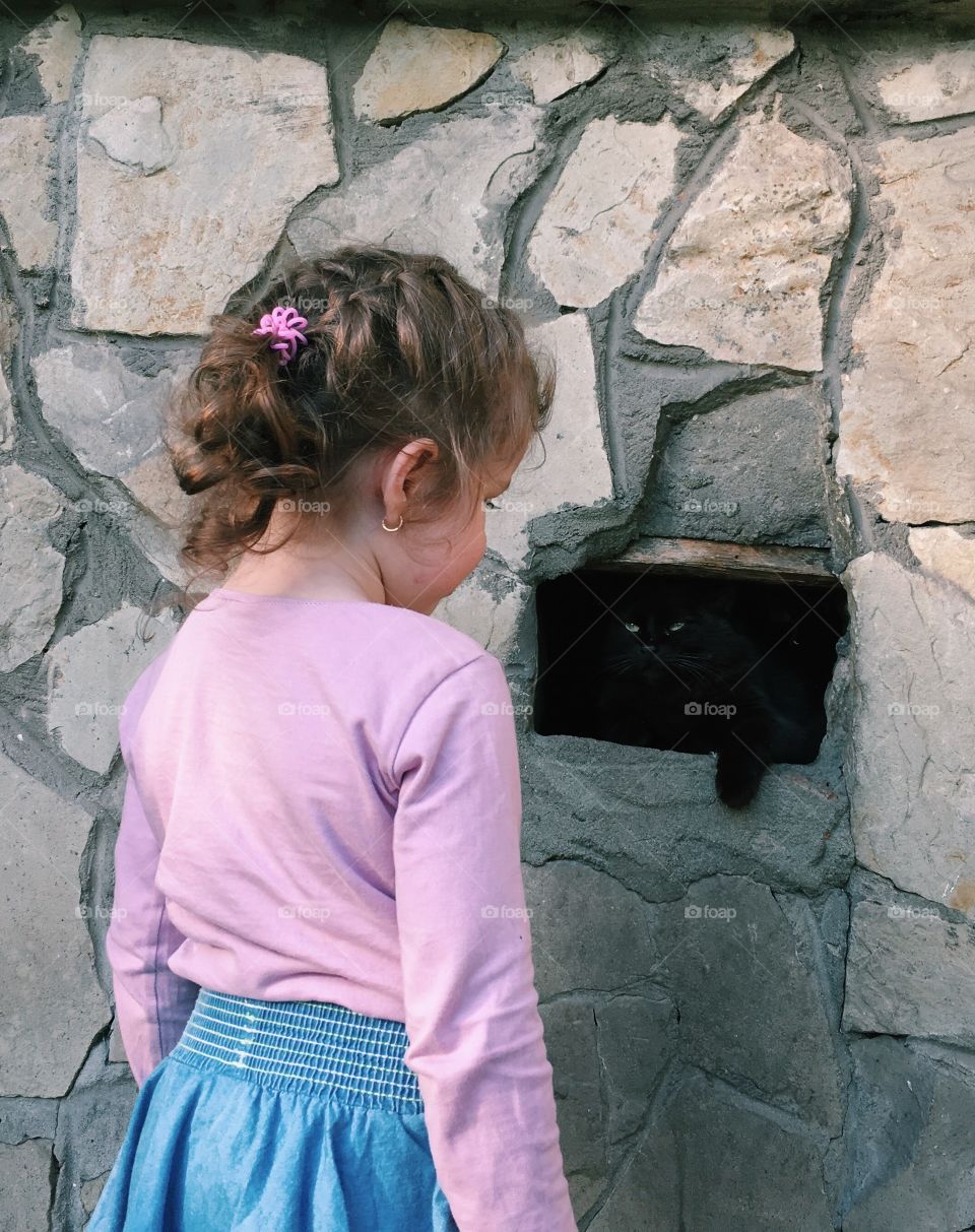 Girl with black cat hiding in the wall 