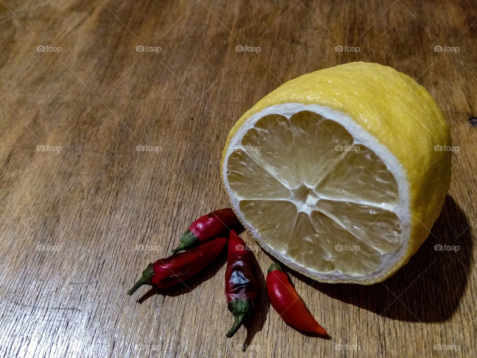 still life with lemon and red pepper on a wooden table. red hot pepper. lemon. fruit. seasoning. spice