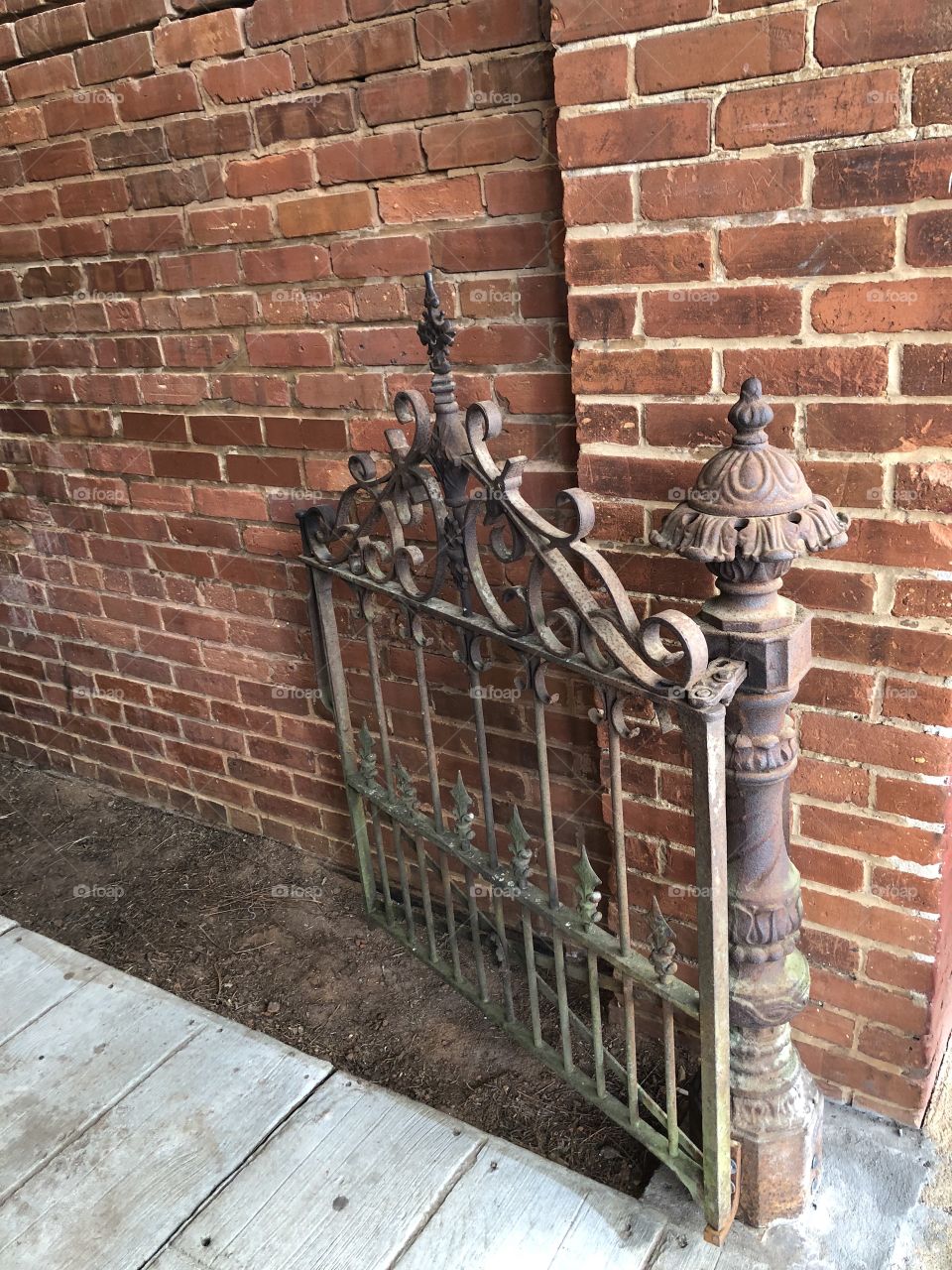 Old iron gate against a very old brick building. 