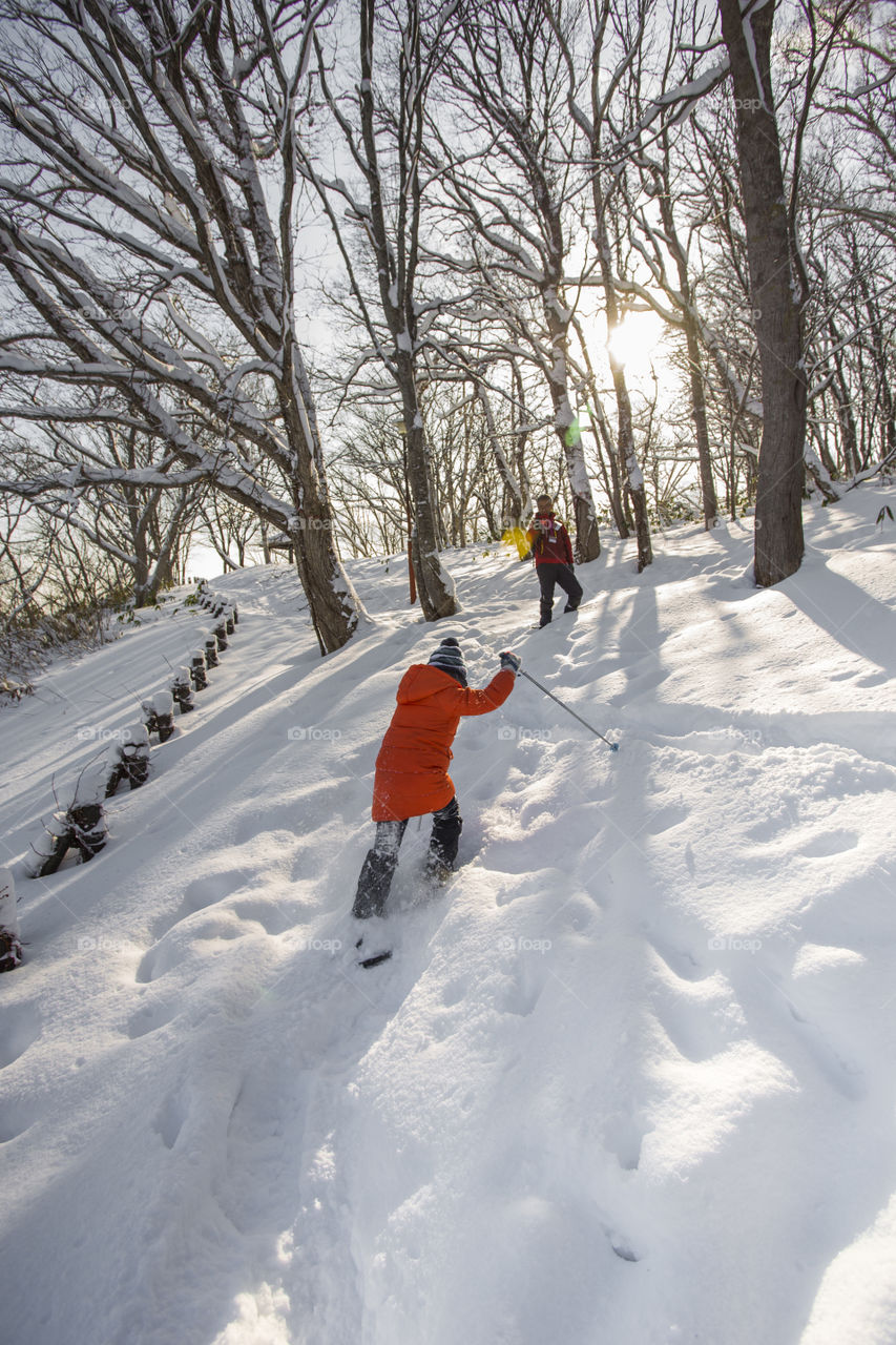 Young boy snowshoe walking on the snow through the forest on a winter sunny day in Sapporo Hokkaido Japan