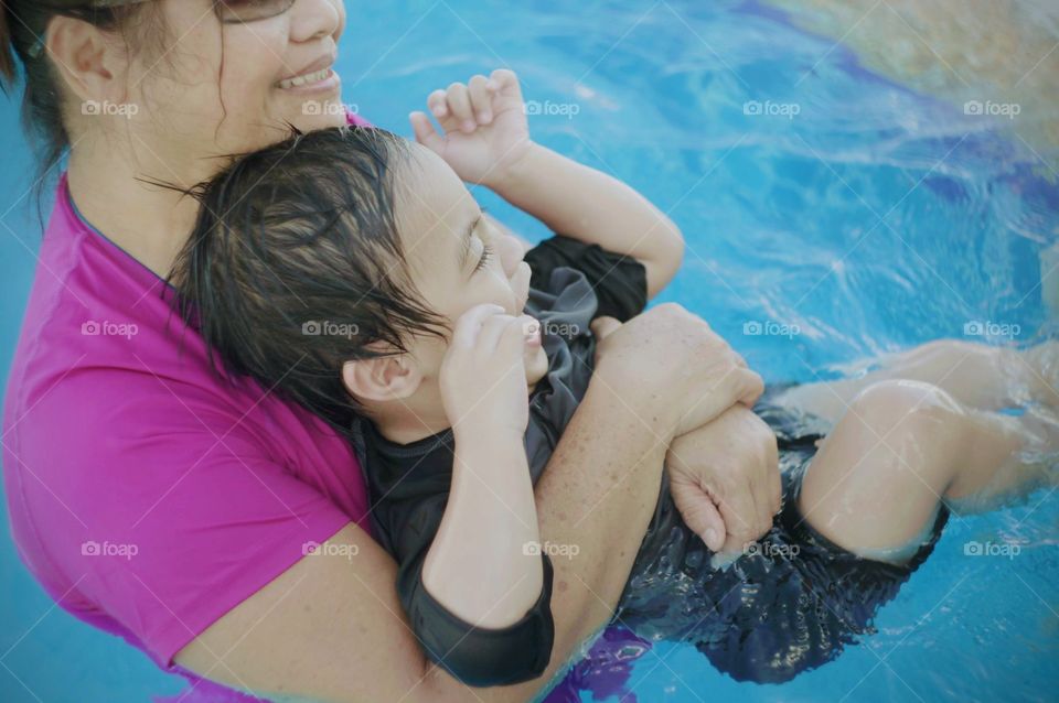Grandma and grandson swimming in the pool.