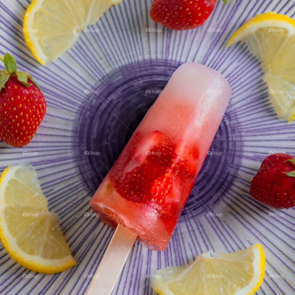 Strawberry and lemon ice lolly on a plate with fruit