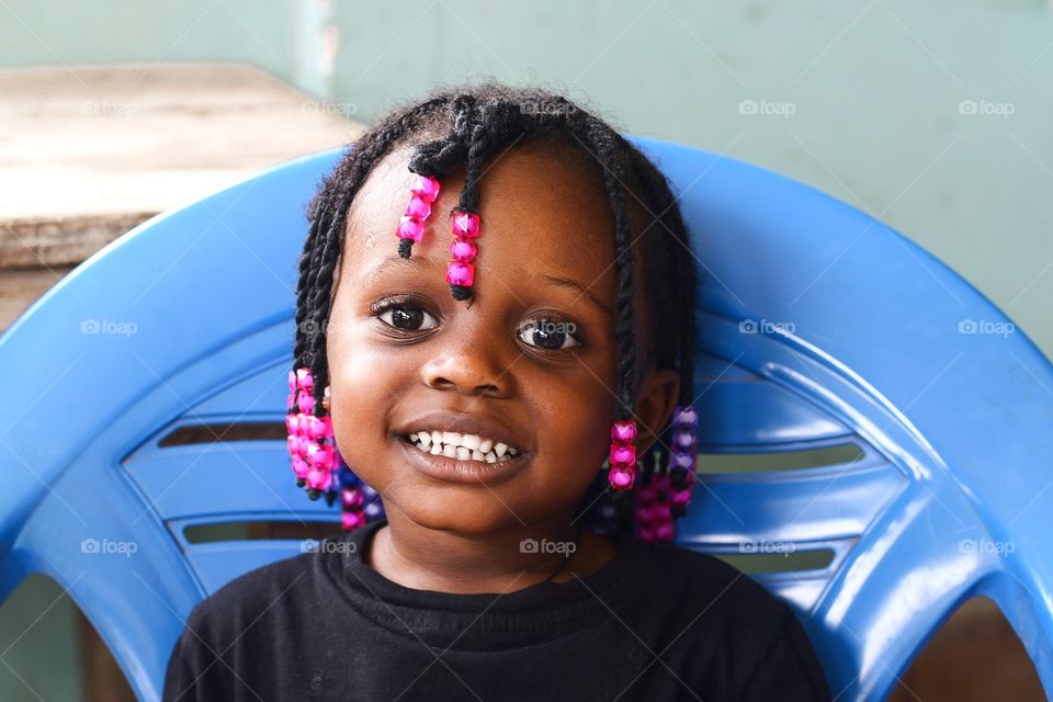 A child in black color shirt smiling with her teeth showing and eyes wide opened.