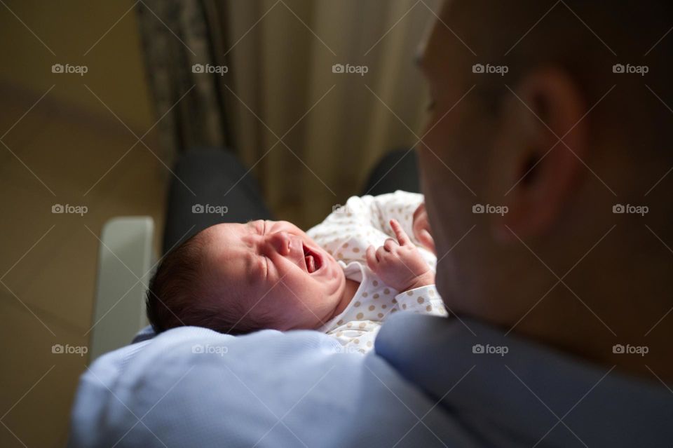 baby girl crying in dad's arms