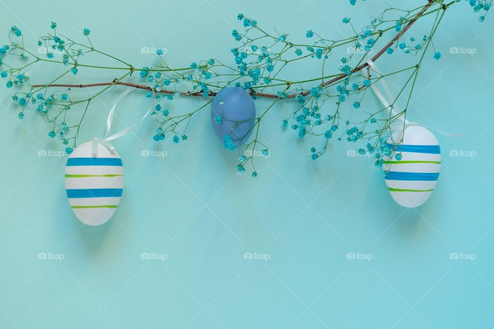 Top view of easter mockup with decorative eggs placed on branch and twigs of blue flowers