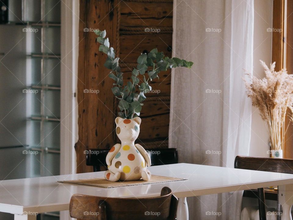 Eucalyptus branches stand in the shape of a bear on a wooden table in a cozy kitchen