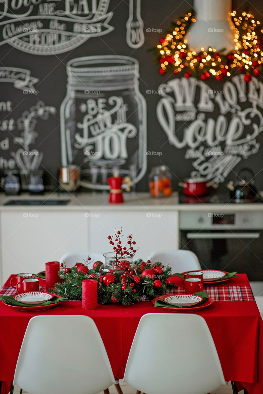 Festive winter cozy kitchen interior with garlands, decorations and gifts.  Christmas dinner at the decorated table.