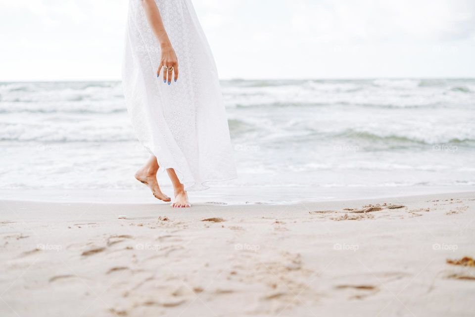 Crop photo of Young beautiful woman in white dress enjoying life on the sea beach
