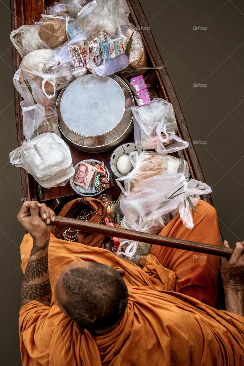 Morning alms for the Buddhist monk paddling in his narrow wooden boat