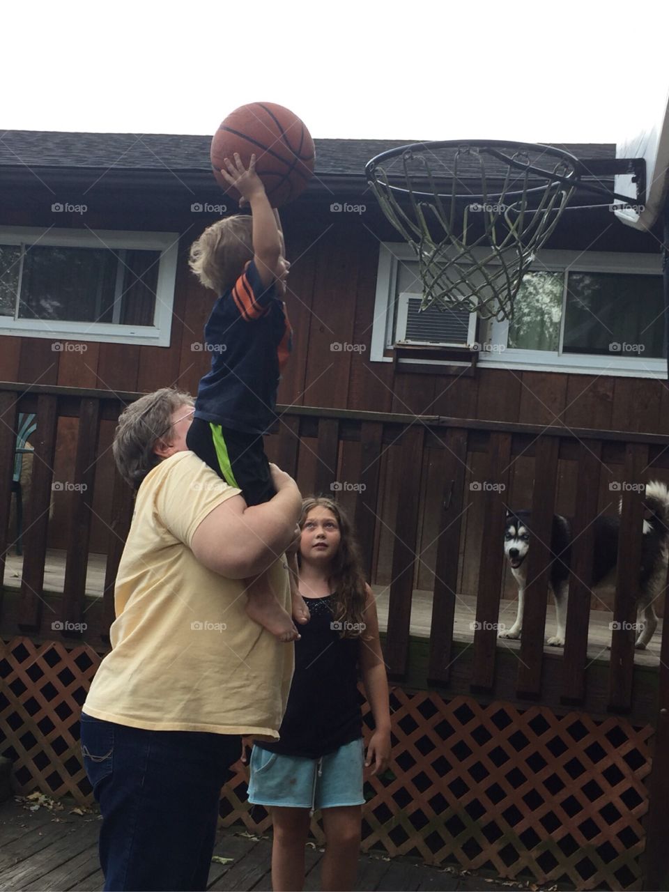 Man carrying his son for putting ball in basketball hoop