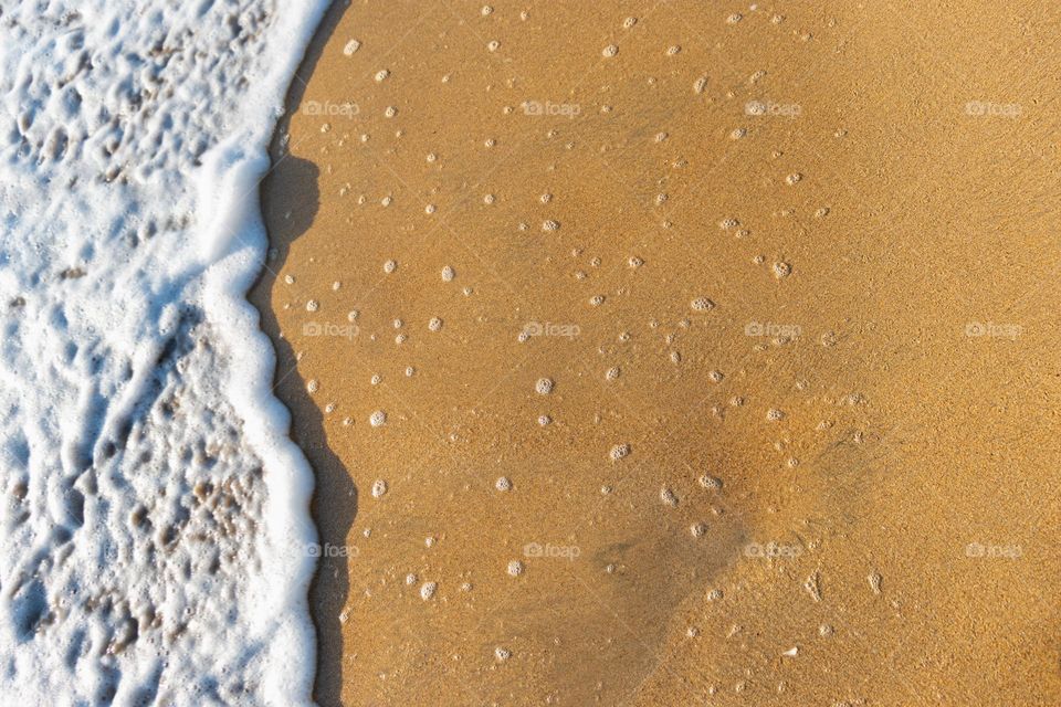 Waves crash into the golden sandy beach, creating beautiful white foam. A perfect summer day in tropical island Sri Lanka.