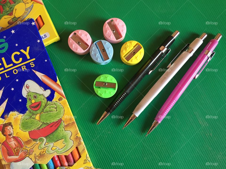 Color pens and sharpeners on green background 