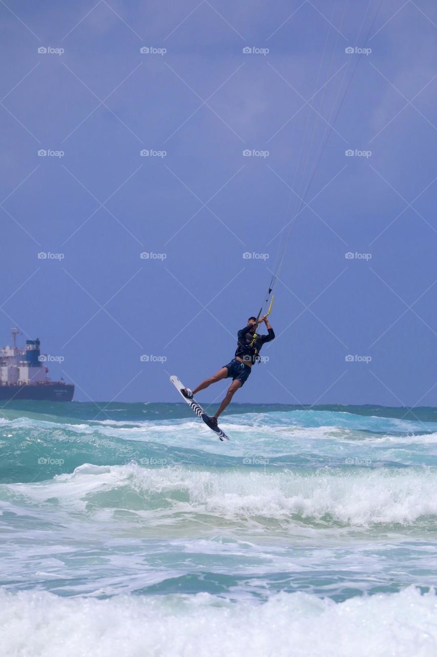 Kite surfer jump above the waves in blue sea at a sunny day