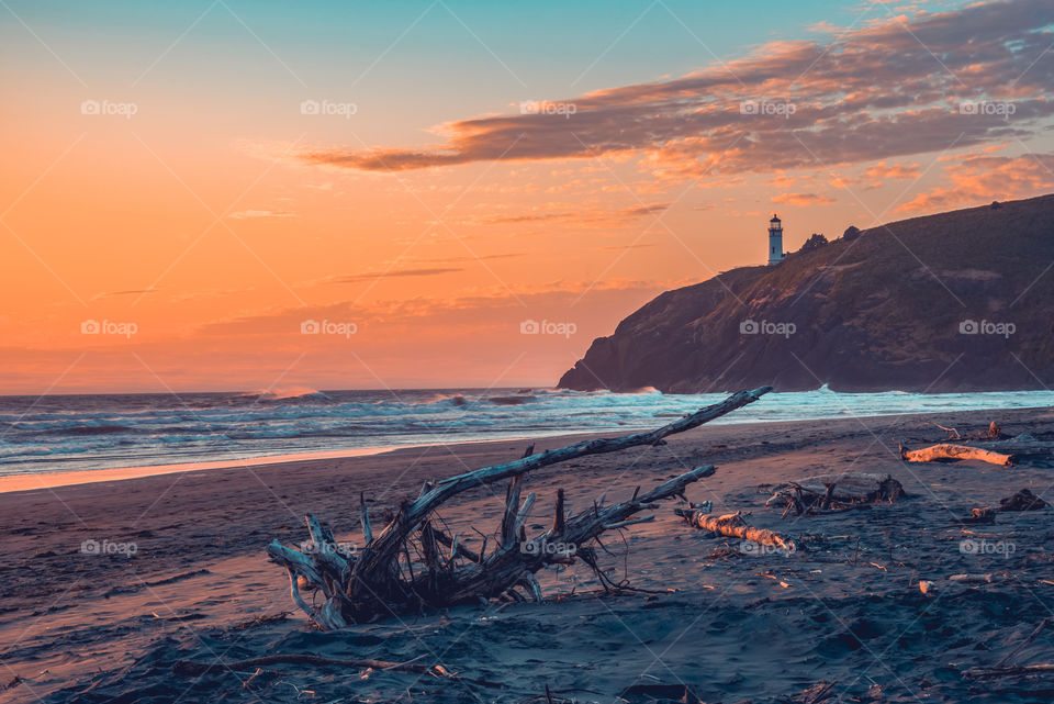 Orange and blue sunset colors at golden hour over a lighthouse on the coast 